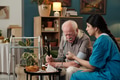 Senior Caucasian Man Receiving Blood Pressure Check from Young Adult Woman - PhotoDune Item for Sale