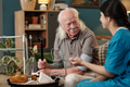 Senior Caucasian Man Smiling While Receiving Blood Pressure Check from Nurse - PhotoDune Item for Sale