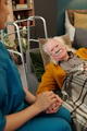 Senior Caucasian Man Lying in Bed Holding Hands with Young Female Nurse - PhotoDune Item for Sale