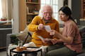 Senior Caucasian Man Sharing Photographs with Young Adult Hispanic Woman - PhotoDune Item for Sale