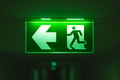 Exit way arrow direction guidance sign green color light emergency exit sign in a dark room - PhotoDune Item for Sale