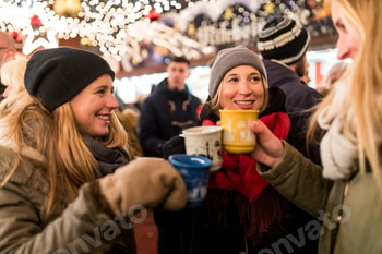 Happy young women with cups of mulled wine at Christmas market in Innsbruck