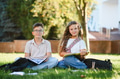 Schoolchildren learning outdoors reading books on campus grass - PhotoDune Item for Sale