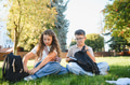 School children sitting on grass packing backpacks - PhotoDune Item for Sale