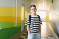 Smiling student wearing backpack standing in school hallway - PhotoDune Item for Sale