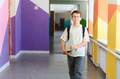 Schoolboy walking in school corridor carrying books and backpack - PhotoDune Item for Sale