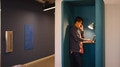 Young Businessman Talking on Phone And Working On Laptop In Pod In Modern Office - PhotoDune Item for Sale