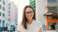 Portrait Of Young Smiling Woman Wearing Glasses Outdoors With City Buildings In Background - PhotoDune Item for Sale