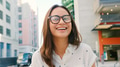 Portrait Of Young Smiling Woman Wearing Glasses Outdoors With City Buildings In Background - PhotoDune Item for Sale