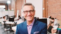 Portrait Of Mature Businessman In Modern Open Plan Office With Business Team Working In Background - PhotoDune Item for Sale
