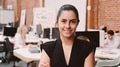 Portrait Of Smiling Young Businesswoman Standing Against Brick Wall In Modern Office - PhotoDune Item for Sale