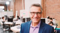 Portrait Of Mature Businessman In Modern Open Plan Office With Business Team Working In Background - PhotoDune Item for Sale