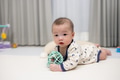 Happy baby lying on carpet playing toy - PhotoDune Item for Sale