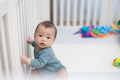 Baby sitting inside crib surrounded by toys - PhotoDune Item for Sale