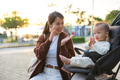 Mother clap with baby while sitting in stroller under sunlight flare - PhotoDune Item for Sale
