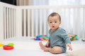 Curious baby sitting in playpen with colorful toys - PhotoDune Item for Sale