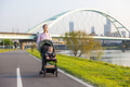 Mum walking with baby on stroller at river park - PhotoDune Item for Sale