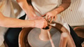 Close Up Of Female Teacher Helping Man Sitting At Wheel In Pottery Class - PhotoDune Item for Sale