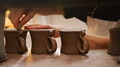 Close Up Of Potter Putting Manufacturers Stamp Onto Bottom Of Clay Mugs In Ceramics Studio - PhotoDune Item for Sale