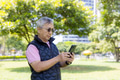 Senior man text messaging through mobile at park - PhotoDune Item for Sale