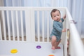 Little baby boy standing in baby playpen - PhotoDune Item for Sale