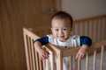 Little baby standing inside crib with playful expression - PhotoDune Item for Sale