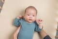 Cute baby lying on soft beige mattress with hands raised - PhotoDune Item for Sale