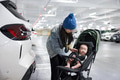 Mother placing baby into stroller in parking lot - PhotoDune Item for Sale