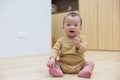 Cute baby sitting on wooden floor smiling happily - PhotoDune Item for Sale
