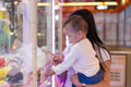 Mother holding baby watching claw machine in arcade - PhotoDune Item for Sale