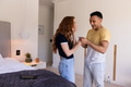 Young couple laughing together while looking at smartphone in cozy bedroom - PhotoDune Item for Sale