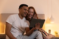 Young couple laughing and video chatting on tablet in cozy bedroom - PhotoDune Item for Sale