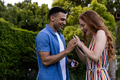 Young man proposing to joyful woman with engagement ring in lush garden - PhotoDune Item for Sale