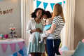 Celebrating baby shower, women holding baby and chatting in living room, smiling - PhotoDune Item for Sale