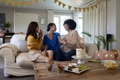 Friends celebrating birthday at home, laughing and enjoying cake on cozy sofa - PhotoDune Item for Sale