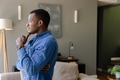 Thoughtful man in blue shirt contemplating at home, looking out window - PhotoDune Item for Sale