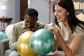 Friends inflating colorful balloons, preparing for festive celebration at home - PhotoDune Item for Sale