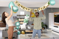Friends decorating living room with balloons and banner for birthday celebration - PhotoDune Item for Sale