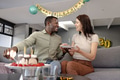 On sofa, African American man and woman sharing birthday cake, smiling warmly - PhotoDune Item for Sale