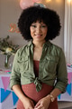 Smiling woman in green shirt celebrating at home with colorful decorations - PhotoDune Item for Sale