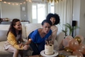 Celebrating birthday, woman blowing candles on cake with friends at home - PhotoDune Item for Sale