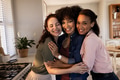 Three women embracing and smiling in kitchen, celebrating friendship and happiness - PhotoDune Item for Sale