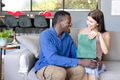 Couple exchanging gifts on sofa, smiling and enjoying joyful moment together - PhotoDune Item for Sale