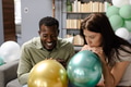 Friends inflating balloons together, preparing for festive celebration at home - PhotoDune Item for Sale