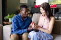 Couple exchanging gift on sofa, smiling and enjoying special moment together - PhotoDune Item for Sale