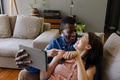 Couple relaxing on couch, smiling and using tablet at home, enjoying time together - PhotoDune Item for Sale