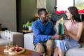 Couple exchanging gifts on sofa, smiling and enjoying celebration at home - PhotoDune Item for Sale