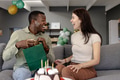 Exchanging gifts, happy couple celebrating birthday with cake and balloons at home - PhotoDune Item for Sale