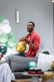 Man joyfully inflating balloons on couch during festive home celebration - PhotoDune Item for Sale