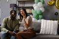 Sitting on sofa with balloons, couple sharing joyful conversation at home - PhotoDune Item for Sale